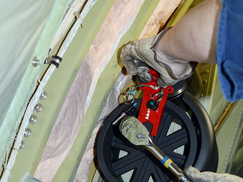 Technician servicing an AMCE negator spring assembly on a C-130 paratroop door